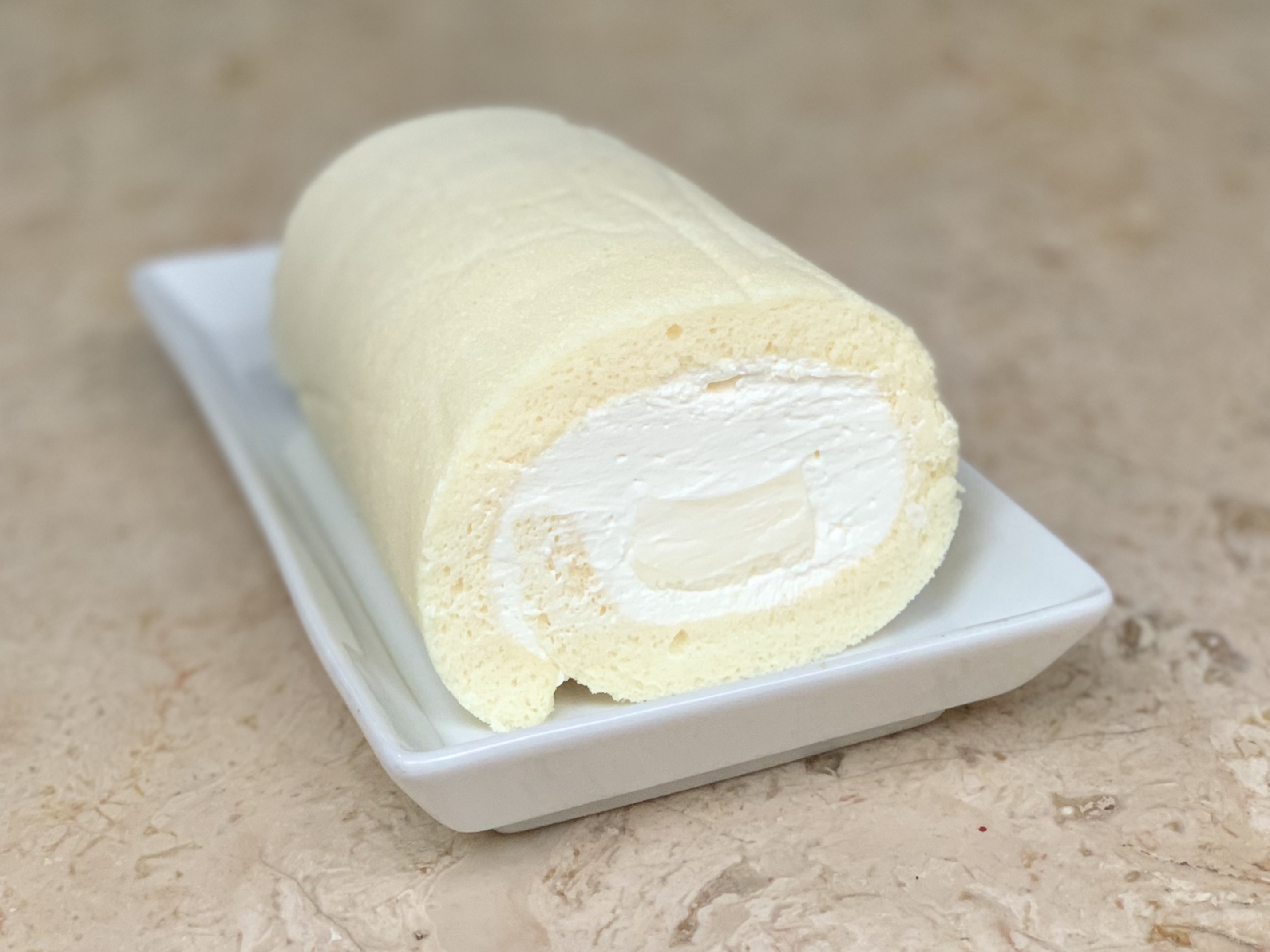 Who would’ve thought chewy candies can take part in the baking of a roll cake? Our parago chewy milk is a great addition to this recipe as it brings out the milky flavor, making it more creamy and savory. This roll cake gets better with every bite, it is super light and soft, making it the perfect go to dessert after a heavy meal!  Ingredients:  Jelly:  30g Full cream milk 20g Heavy cream 3 pieces of PARAGO® Milk Chewy Candy 2g Gelatin powder 15g Cold water Cream:  55g Heavy cream 35g Full cream milk 6 pieces of PARAGO® Milk Chewy Candy 160g Whipping cream Sponge Cake:  35g Full cream milk 15g Vegetable oil 2g Vanilla extract 35g Cake flour 135g Egg whites 45g Caster sugar Instructions:  Jelly:  Sprinkle gelatin powder on the cold water and mix until there are no lumps. Set aside to bloom for 5 minutes. Meanwhile, put the milk, heavy cream, and PARAGO®️ Milk Chewy Candies in a saucepan and place it on a stove that is set on low heat. Stir the mixture until the candies are all melted. Microwave the bloomed gelatin for 10 seconds, then take it out and stir the mixture. Put it back in the microwave for another 10 seconds. Take it out and mix until all the gelatin has dissolved. Pour the dissolved gelatin into the milk, heavy cream, and candy mixture. Stir until combined. Line a 10cm x 5cm mold or container with heat-proof plastic wrap. Pour the jelly into the mold, let it cool slightly, then cover and place it into the fridge for at least 8 hours. Cream:  Pour the milk, heavy cream, and PARAGO®️ Milk Chewy Candies in a saucepan and place it on a stove that is set on low heat. Stir the mixture until the candies are all melted. Then, pour the mixture into a bowl and cover the surface directly with heat-proof plastic wrap. Let it cool slightly, then chill in the fridge for at least 8 hours. After fully chilled, combine the candy mixture with the whipped cream in a bowl, and beat them together with an electric mixture using the whip attachment until medium peaks. Cover the bowl with plastic wrap, then place it in the fridge for later use. Sponge Cake:  Preheat the oven to 160°C. Grease a 22cm x 22cm square pan with vegetable oil, then line all the sides of the pan with parchment paper. In a bowl, mix the milk and the vegetable oil with a whisk until emulsified, then add the vanilla extract and whisk until combined. Sift in the cake flour and whisk until there are no more lumps. In a separate bowl, whip the egg whites with an electric mixer until bubbly. Then, gradually add the castor sugar while continuously mixing. When all the sugar is added, keep mixing until the mixture reaches medium peaks. Take 2 scoops of the egg white mixture and mix it with the batter using the whisk. After combined, continue to add in ½ of the egg whites. Fold the mixture with a spatula gently until they are almost combined. Add the remaining egg whites, then fold the mixture again until fully combined. Pour the batter into the cake pan, then bake it in the oven for 15 minutes. Cool it on a rack completely before handling. Assembling the Roll Cake:  Take the jelly out of the mold and cut it lengthwise into 2 equal strips. Carefully take the cooled sponge cake out of the pan. Turn the cake pan over, then place the cake on top of the inverted cake pan. Next, turn the cake over onto a piece of parchment paper that is bigger than the cake. Peel of all the parchment paper, then cut the right and left edges of the cakes with a serrated knife.  Spread ⅔ of the cream on the cake. Place the jelly strips on top of the cream on 1 end of the cake that will be rolled. Cover the jellies with the remaining cream and shape the cream into a mountain to keep the shape of the roll cake circular and not flat. Roll the cake with the help of the parchment paper. Wrap the roll cake with the parchment paper and let it set in the fridge for at least 4 hours. Before serving, cut the edges of the roll cake with a serrated knife to reveal the inside. Recipe Created By: Kathleen.Z.B Instagram: @zanetta.kitchen